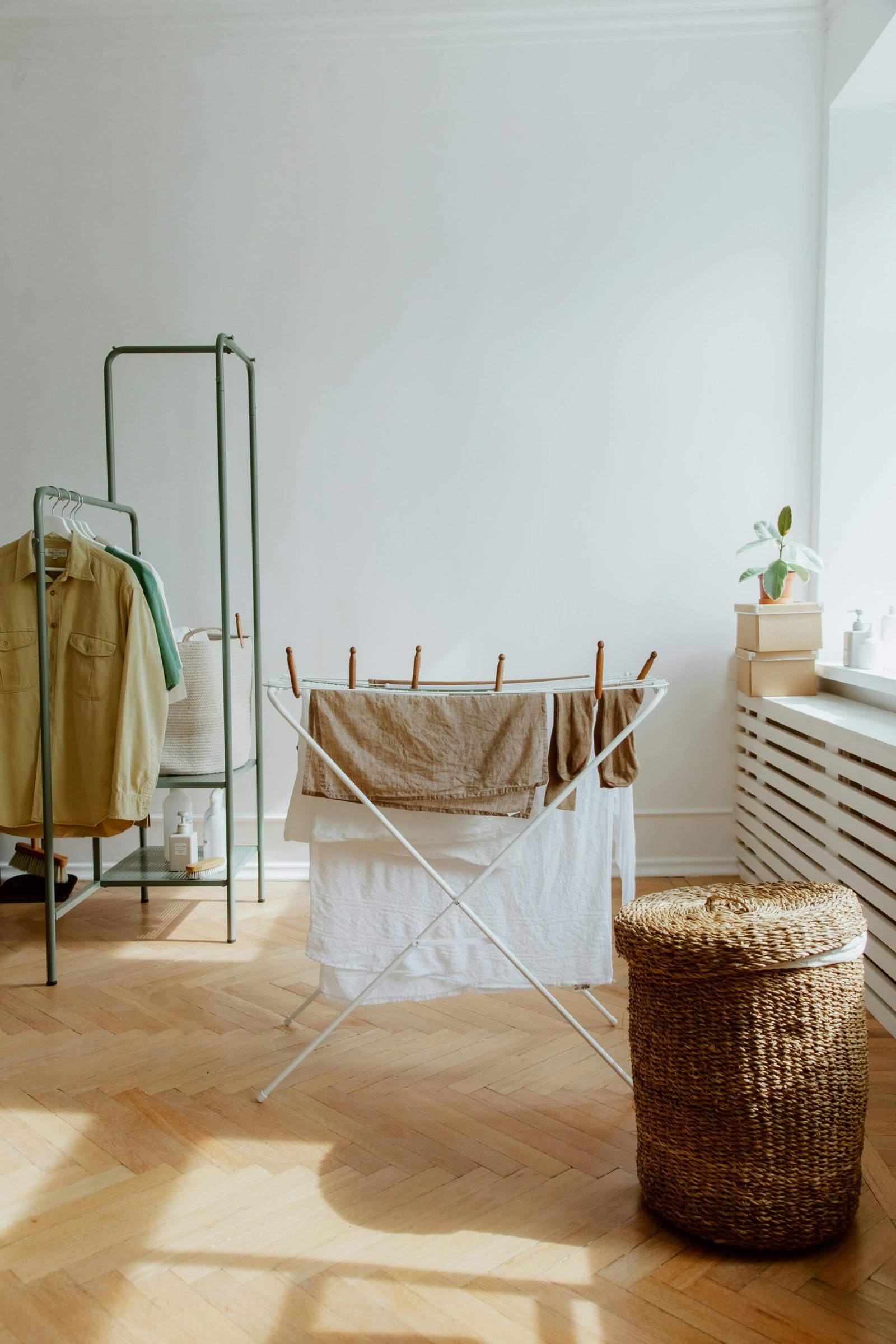 A tidy laundry room with clothes drying and a wicker basket in sunlight.