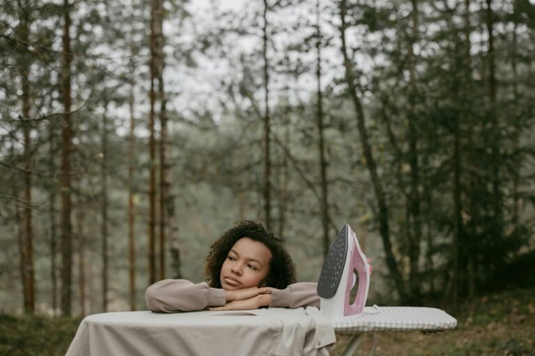 A woman rests on an ironing board outdoors, capturing a moment of daydreaming.